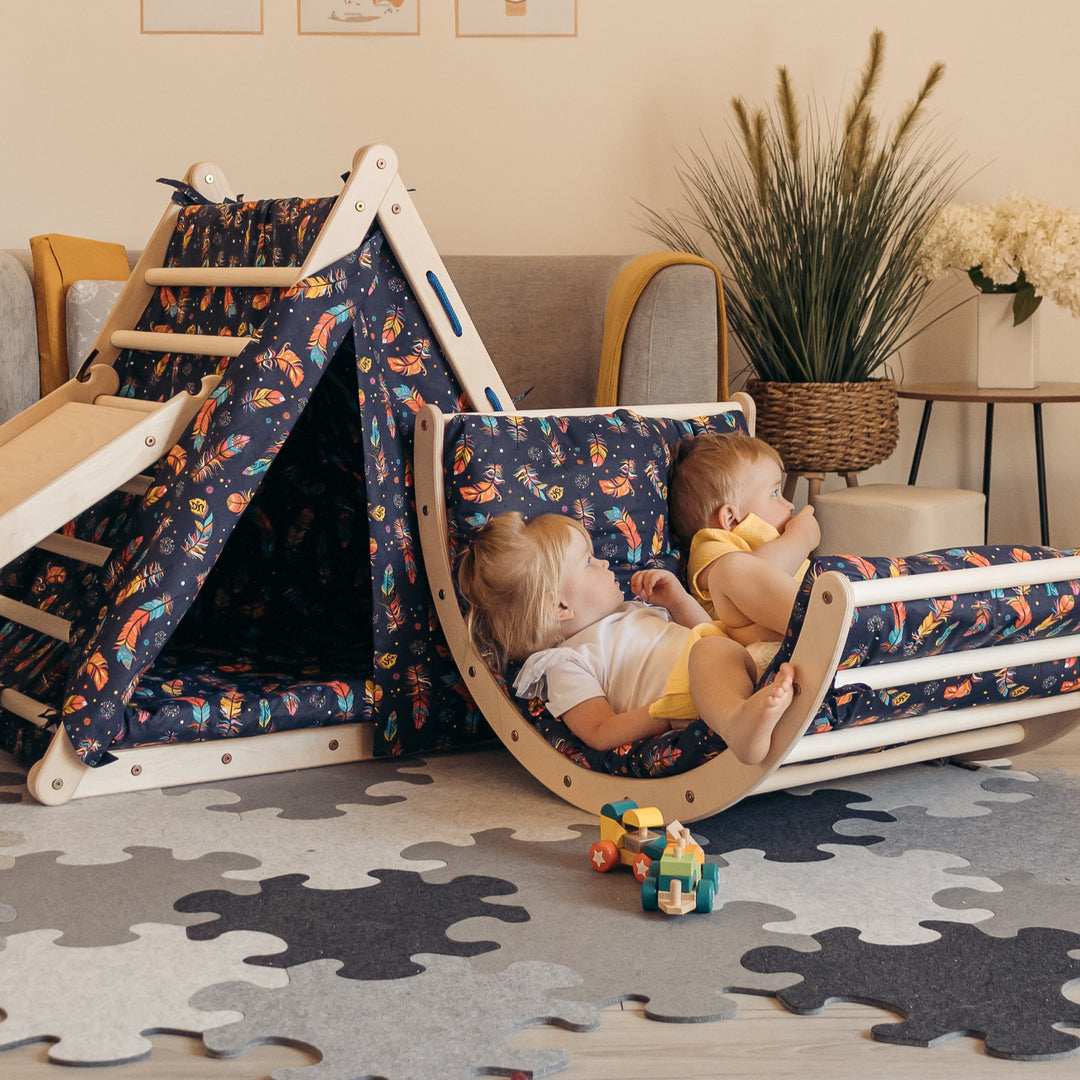 Two young children playing with a climbing and swing set accessory in a room with a puzzle mat underneath.