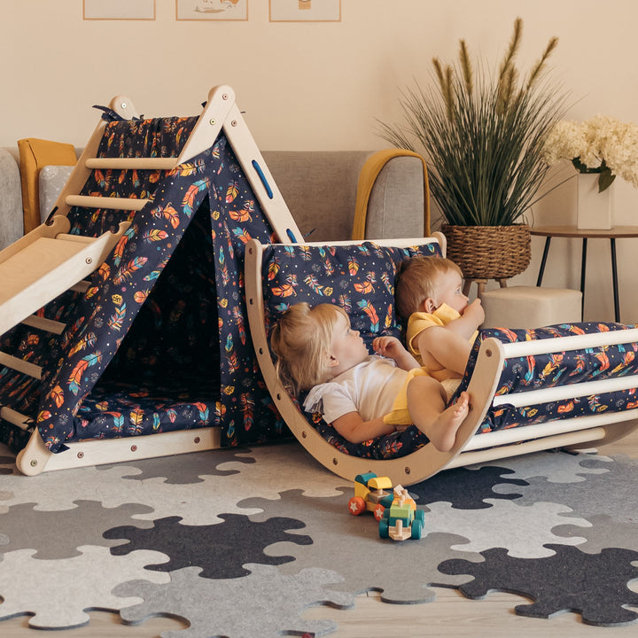 Two young children playing with a climbing and swing set accessory in a room with a puzzle mat underneath.