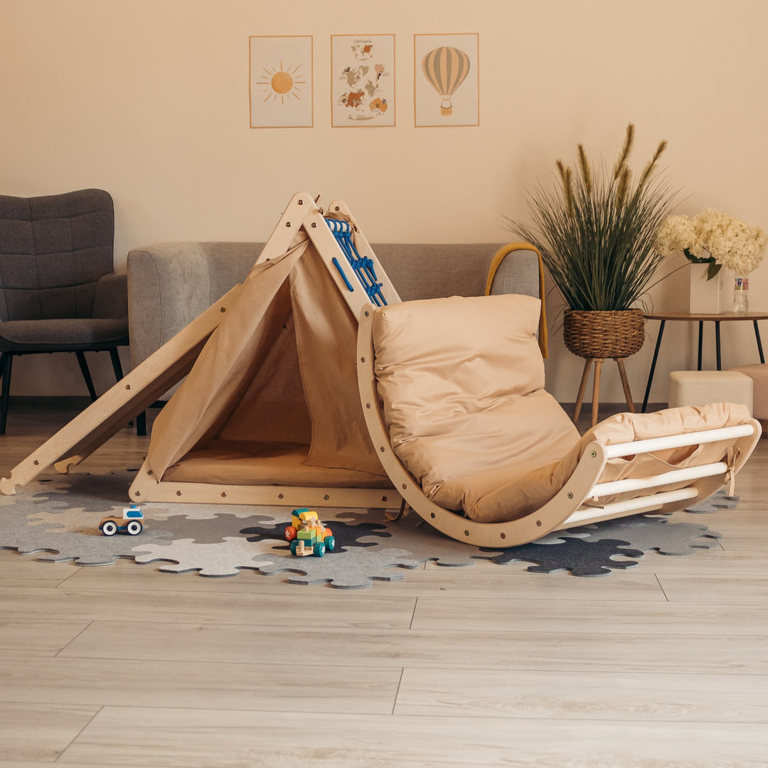 Children's climbing set with a triangle, sliding board, arch, tent, and two mattresses arranged on the floor, with toys and decorative items in the background.