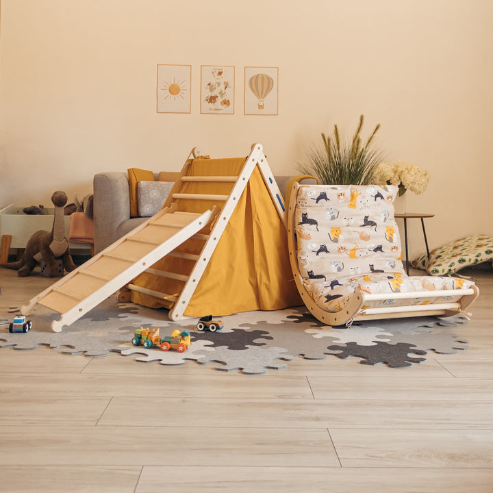 Children's climbing set with triangle, sliding board, arch, tent, and two mattresses arranged on the floor, with toys scattered around. 