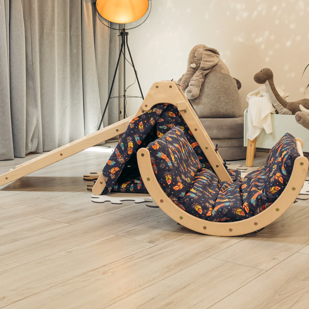 A foldable wooden triangle children's playset with multicolored padding, including a sliding board and a tent.