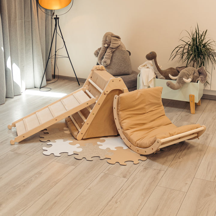A fold-up playset for babies and toddlers including a triangle, a sliding board, and a tent made of brown fabric, complemented with brown mattresses.